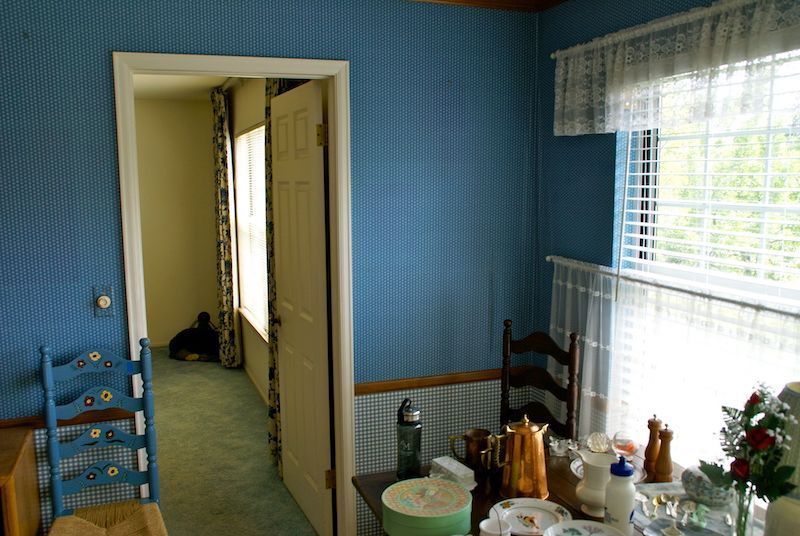 Blue dining room with table, chairs, wallpaper, door, and window with blinds.