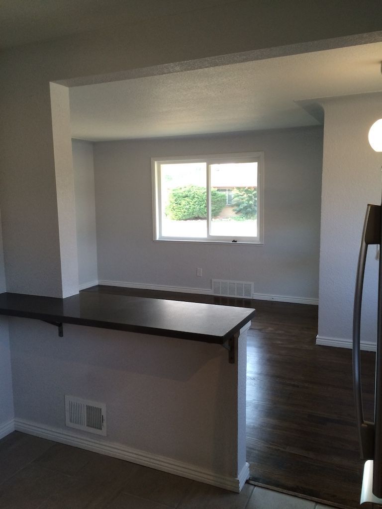 Interior view of a remodeled home with a dark wood bar and a window overlooking greenery. Gray walls, dark wood floors.