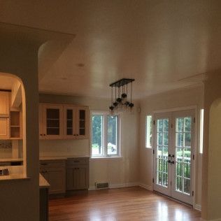 Dining room with wooden floor, cabinets, French doors, and a chandelier.