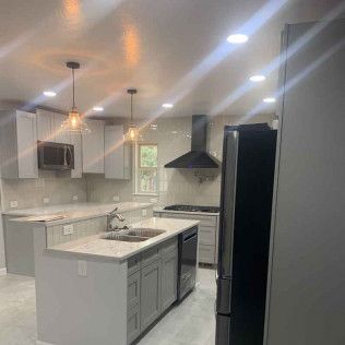 Modern kitchen with gray cabinets, island, stainless steel appliances, and pendant lights.