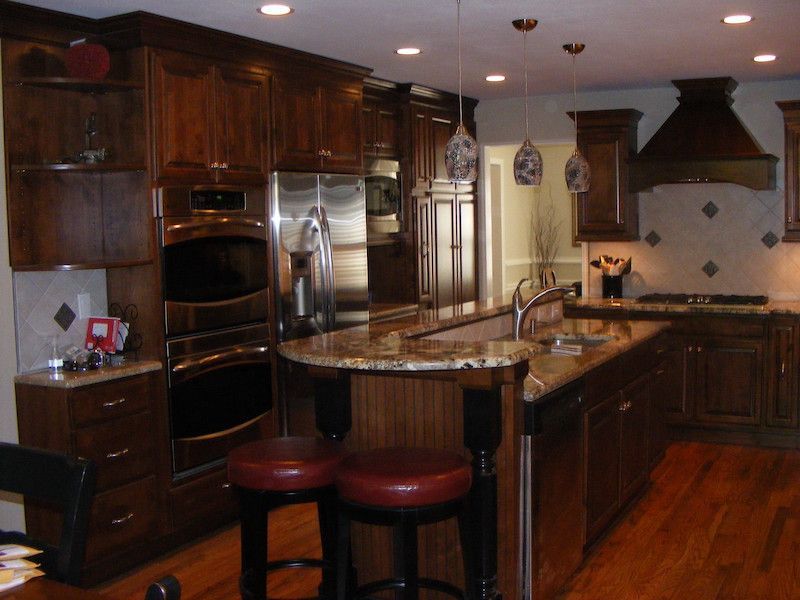 Dark wood kitchen with granite countertops, stainless steel appliances, and pendant lights.