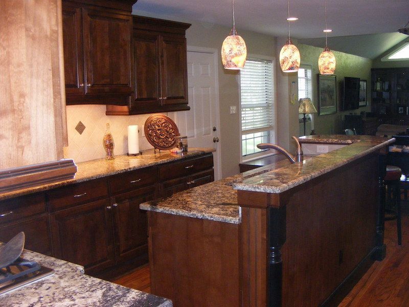 Dark wood kitchen with granite countertops, pendant lights, and island.