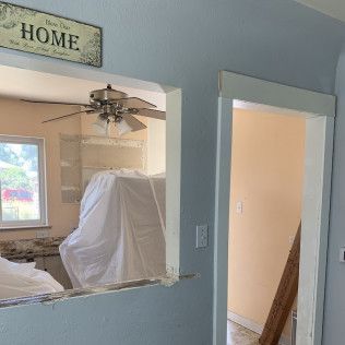 Interior view of a renovated kitchen with blue walls, open doorways, and a 