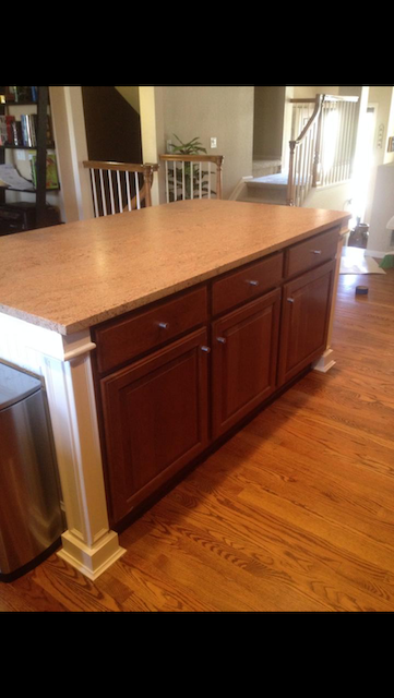 Kitchen island with brown cabinets, tan countertop, and white accents, on a hardwood floor.