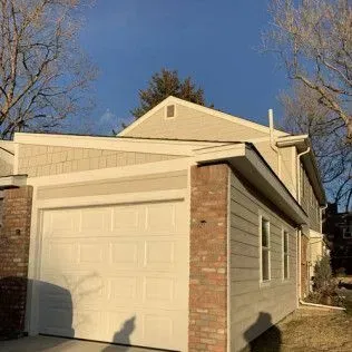 Tan and brick two-story building with a garage, under a blue sky.
