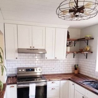 Kitchen with white cabinets, wood countertops, and subway tile backsplash.