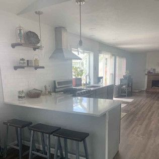 Modern kitchen with island, stools, stainless steel appliances, and wood floors.