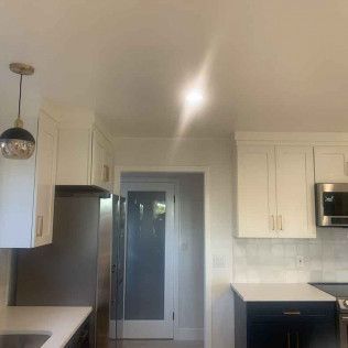 Kitchen with white cabinets, stainless steel refrigerator, and dark blue island.