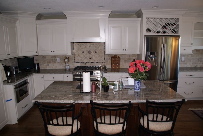 Kitchen with white cabinets, granite countertops, and a central island with bar stools.