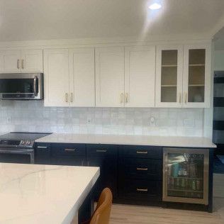 Modern kitchen with white upper cabinets, dark lower cabinets, and a white countertop.