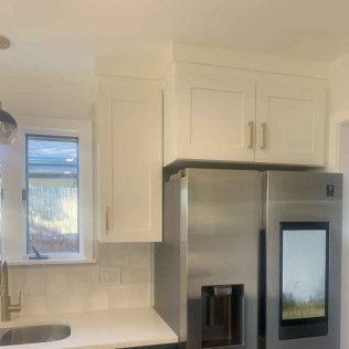 Kitchen with white cabinets, gold hardware, and a stainless steel refrigerator.