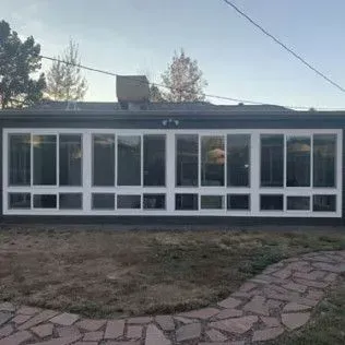 Long, white-framed windows across the side of a building, under a dark roof.