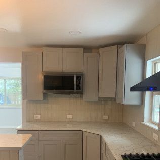 Kitchen with gray cabinets, a microwave, and a white countertop.