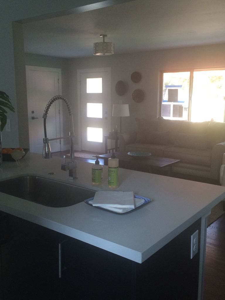 Kitchen island with sink and faucet, view into living area, light streaming from window.
