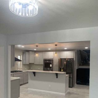 Interior view of a modern kitchen with gray cabinets, stainless steel appliances, and a central island.