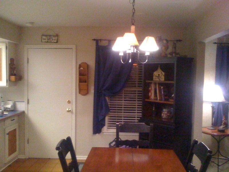 Dining room with wooden table, black chairs, and dark blue curtains.