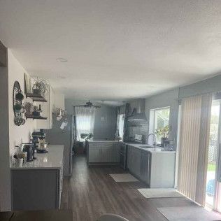 Gray and white kitchen with wood-look flooring, cabinets, and appliances. Sliding glass door on the right.
