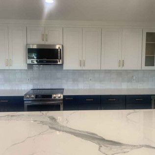 Kitchen with white upper cabinets, stainless steel appliances, and dark lower cabinets.