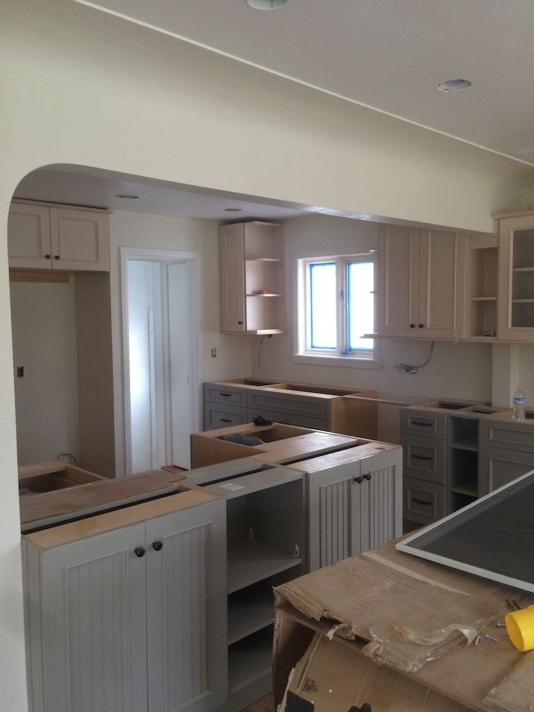 Kitchen under renovation with light cabinets and gray island.