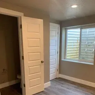 Interior of a room with two closed white doors, a window, and gray walls.