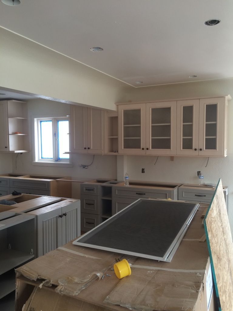 Kitchen with light-colored cabinets, windows, and countertops under construction.