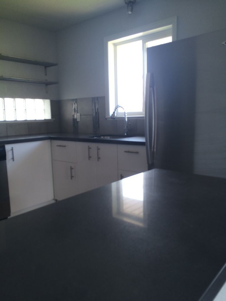 Kitchen with white cabinets, dark countertop, stainless steel appliances, and a window.