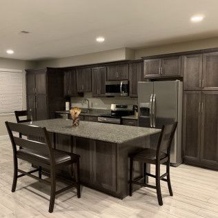 Dark wood kitchen with island, stainless steel appliances, and seating.