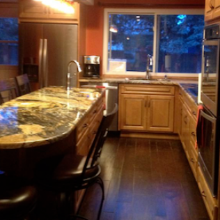 Kitchen with granite countertop island, wood cabinets, and large window.