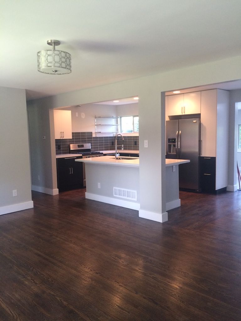 Modern kitchen and living space with dark wood floors and stainless steel appliances.
