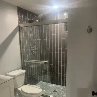 Bathroom with a tiled shower stall and a toilet.
