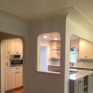 Archways into a renovated kitchen: cabinets, appliances, and countertops in a modern design.