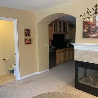 Interior view of a living room with a fireplace, archway, and hallway leading to a bathroom.