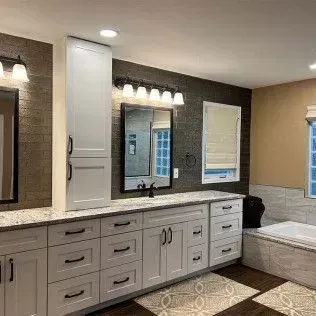 Bathroom with white cabinets, dark accent wall, two mirrors, and a tub.