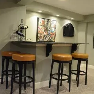 A home bar with four stools, a wine rack, and abstract artwork.