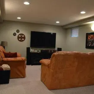 Living room with orange couches, TV, and decorative wall art.
