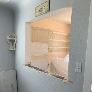 Interior view of an open pass-through. The opening is in a blue wall. The other side is unpainted.