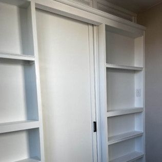 White built-in shelves and a sliding door, likely for storage, painted white.