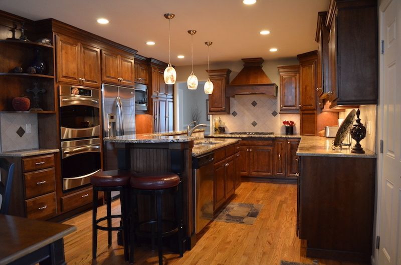 Kitchen with dark wood cabinets, stainless steel appliances, and island with bar stools.