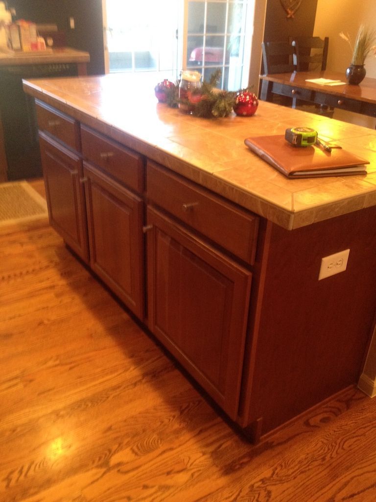 Kitchen island with brown cabinets, light countertop, and hardwood floor.