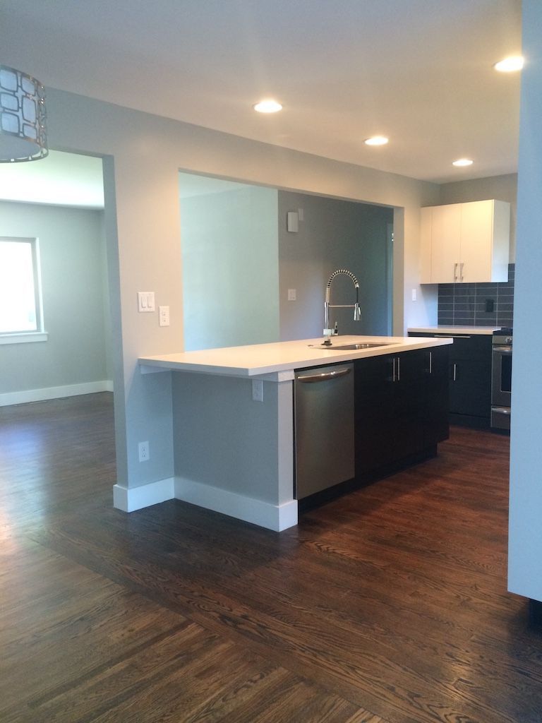 Kitchen with island, hardwood floors, dark cabinets, stainless steel appliances, and white countertops.
