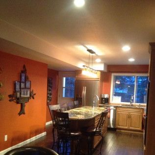 Orange-walled kitchen with a dark wood floor, kitchen island, and stainless steel appliances.