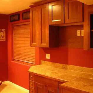 Kitchen with red walls, brown cabinets, and a window with blinds.