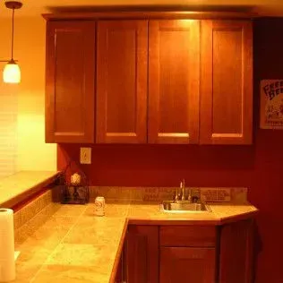 Kitchen with wood cabinets, countertop, sink, and red wall.