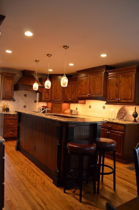 Dark wood kitchen with island, pendant lights, and bar stools.