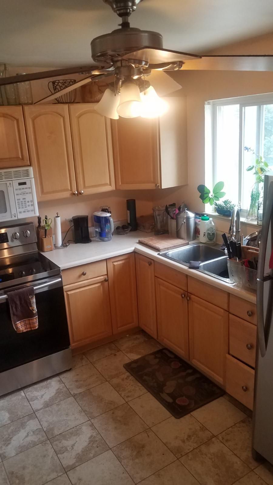 Kitchen with light wood cabinets, stainless steel appliances, and a ceiling fan.