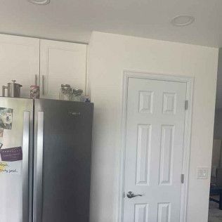 Kitchen with white cabinets, stainless steel refrigerator, and white door.