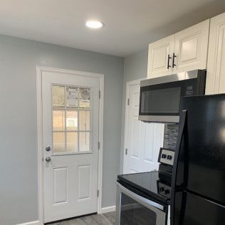 Kitchen with white cabinets, appliances, and door with glass panels.