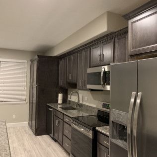 Kitchen with dark gray cabinets, stainless steel appliances, and a light-colored floor.