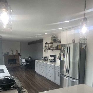 Modern kitchen with stainless steel appliances, light cabinets, wood floors, and island.