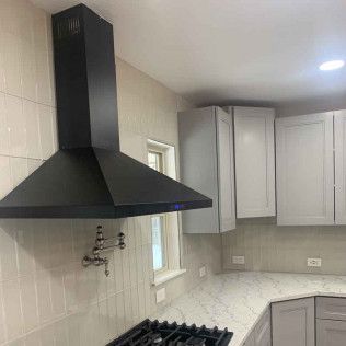 Black range hood in a kitchen with gray and white cabinets.